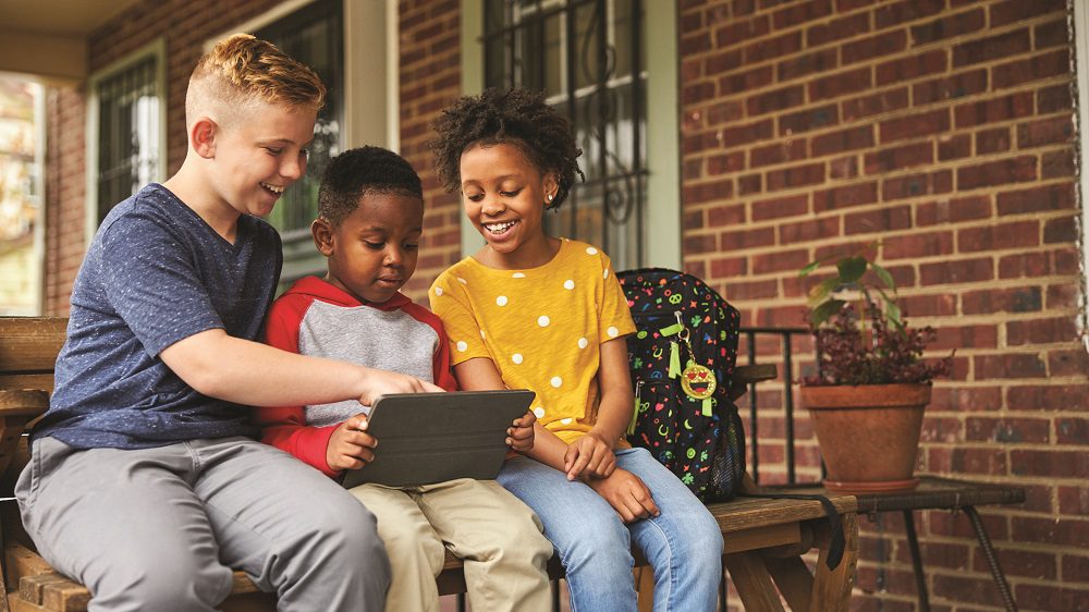 Three children sit together on a porch.